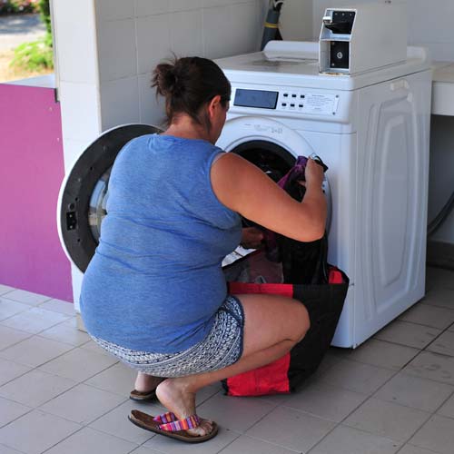 Campista poniendo su ropa en la lavadora del camping de las Landas