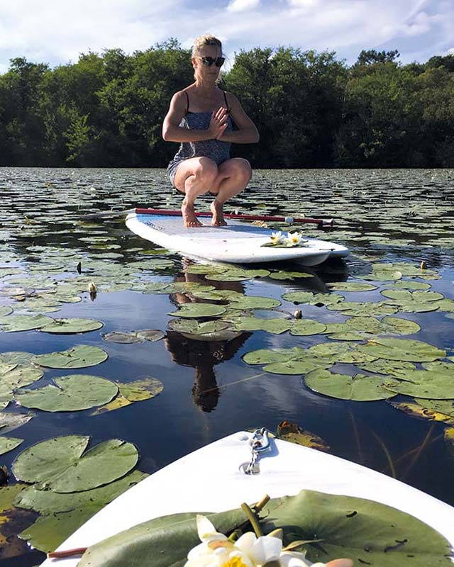 Femme sur un surf en posture de yoga dans les Landes à Messanges